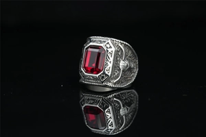 Macro shot of silver titanium eagle ring with large emerald-cut ruby stone and relief work