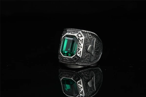 Detailed relief of vintage eagle ring with emerald-cut green stone on mirror surface