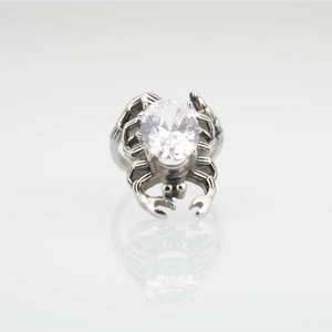 Gothic silver crab ring with a large oval clear crystal on a reflective surface