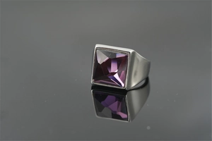 Gros plan d'une bague en argent avec une grande pierre violette carrée sur socle miroir
