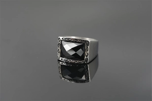 Detail of vintage silver titanium steel ring with rectangle black stone and carved pattern