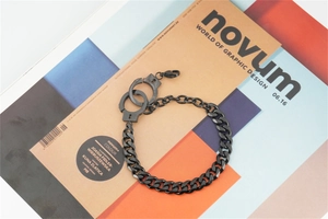 Detail view of black stainless steel handcuff charm and thick Cuban link chain texture