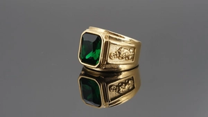Macro detail of men's gold plated dragon ring with a large rectangular green gemstone
