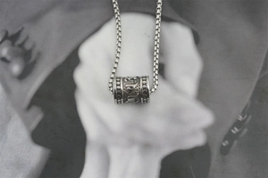 Vue macro d'un pendentif cylindre rétro en argent avec gravure de mantra bouddhiste