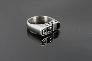 Macro detail of industrial silver lighter-shaped ring on a dark reflective surface