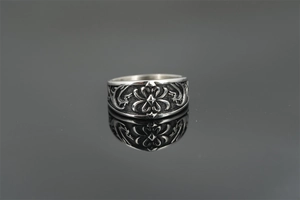 Detail shot of wide vintage titanium steel ring with gothic floral carvings and reflections