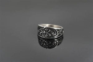 Detail of vintage silver titanium steel ring with intricate punk floral carvings and reflections