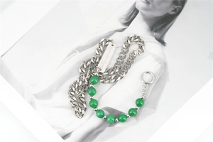 Detailed macro view of heavy cuban chain necklace with green beads and engraved metal tag
