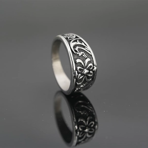 Vintage gothic titanium steel ring with intricate floral carvings on a reflective surface