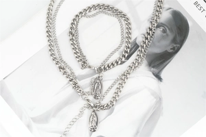 Close-up of silver layered curb chain necklaces with vintage Virgin Mary pendants