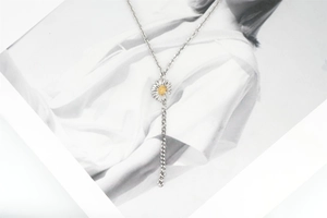 Detail of silver daisy necklace with yellow center on a fashion magazine background