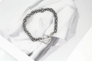 Dettaglio di un bracciale a catena vintage in argento ossidato con elegante chiusura a barra T