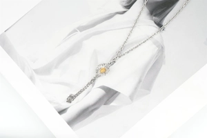 Detailed close-up of a silver sunflower necklace with a yellow core on a portrait page