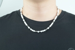 Close-up of pearl and silver bead necklace on model with minimalist style design