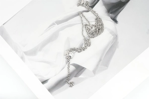 Close-up of minimalist silver titanium sunflower necklace on a stylish poster background