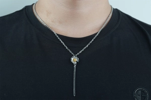 Detail view of a vintage sunflower pendant on a black shirt for a minimalist hip-hop style