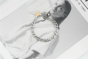 Detailed close-up of a chunky silver chain bracelet with a gold religious cross pendant