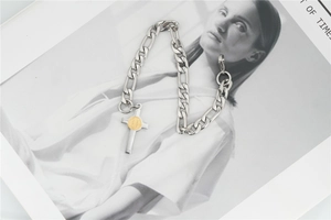 Close-up of silver Figaro chain bracelet with gold St. Benedict cross pendant