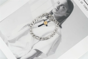 Detailed macro view of a silver Figaro chain bracelet with a gold-tone cross pendant