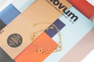 Dettaglio di un bracciale a doppio strato in titanio dorato con anelli incisi LOVE