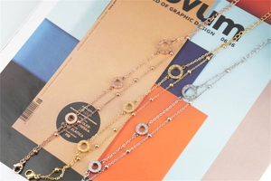 Dettaglio di braccialetti a doppia catena in oro rosa, oro e argento con ciondoli LOVE