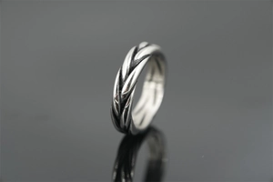 Macro view of retro silver twist ring with detailed braided wheat pattern and polished finish