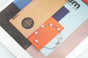 Détail du bracelet double couche en acier inoxydable avec perles blanches et fermoir