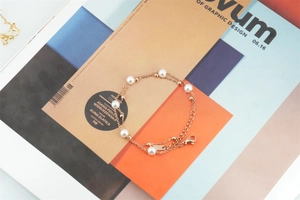 Détail d'un bracelet double couche en or rose avec perles, fermoir mousqueton et chaînette