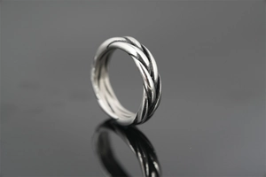 Macro shot of silver vintage twisted rope ring with oxidized finish on black reflective surface