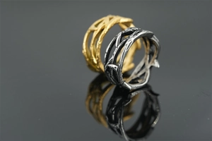 Macro shot of thorn vine pattern ring with vintage texture on a black reflective surface