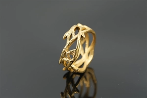 Macro shot of a golden branch ring with intricate organic textures on a black background