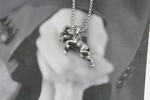 Close-up of vintage titanium steel ram pendant with intricate oxidized metal texture
