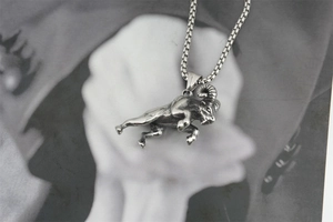 Detail of vintage silver ram pendant in titanium steel with box chain on artistic background