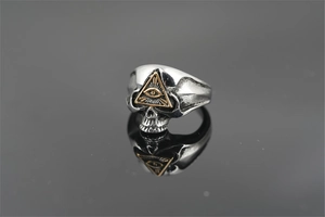 Détail macro d'une bague crâne vintage avec l'œil de la providence doré poli