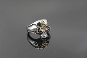 Détail macro d'une bague tête de mort vintage en titane avec l'œil de la providence doré