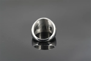 Close-up of a punk-style stainless steel ring with gold stud accents on a black surface