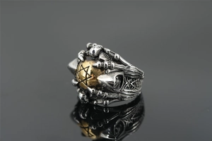 Macro shot of gothic bone claw ring featuring a gold star sphere and skull relief details