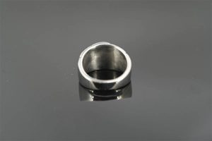 Macro shot of silver wide band metal ring with polished surface and inner reflection