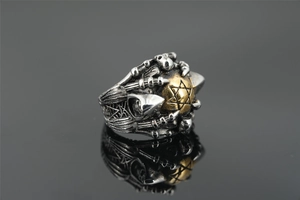 Macro detail of gothic skeletal claws holding a golden orb with Hexagram engraving