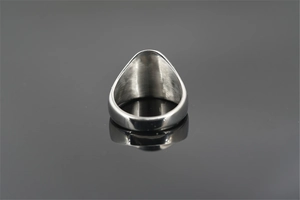 Macro view of wide silver skull ring showing brushed metal texture and smooth inner band