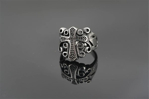 Detail of vintage silver cross ring with intricate filigree texture and mirror reflection