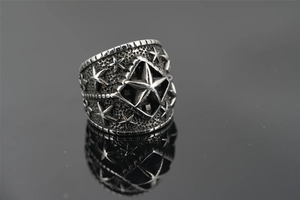 Detail of wide punk style stainless steel ring with vintage star patterns and dark finish