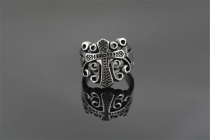 Macro shot of vintage titanium steel cross ring with intricate scrollwork and mirror reflection