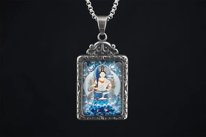 Close-up of a silver Thangka Buddhist pendant with colorful deity art and floral relief