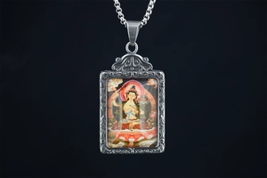 Macro shot of silver Buddha pendant with intricate relief and colorful thangka art