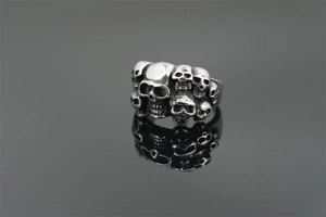 Detailed close-up of punk style skull ring in antique silver finish with mirror reflection