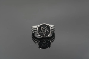 Macro view of vintage titanium steel ring with silver pentagram on black background