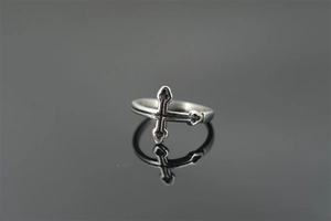 Macro shot of vintage silver cross ring with black oxidized finish on mirrored surface