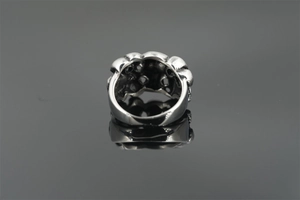 Macro view of wide vintage silver skull ring with textured metal surface and dark reflections