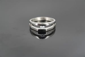 Close-up of double-layer silver ring with single diamond setting on reflective black surface